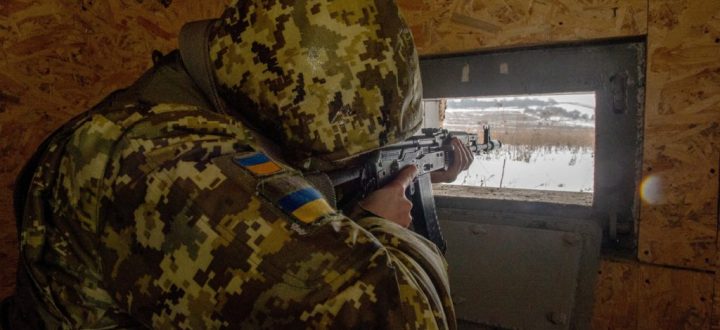 Ukrainian frontier guard aims his rifle from a dugout along the border with Russia, some 40 kms from the second largest Ukrainian city of Kharkiv, on February 7, 2022. (Photo by Sergey BOBOK / AFP)